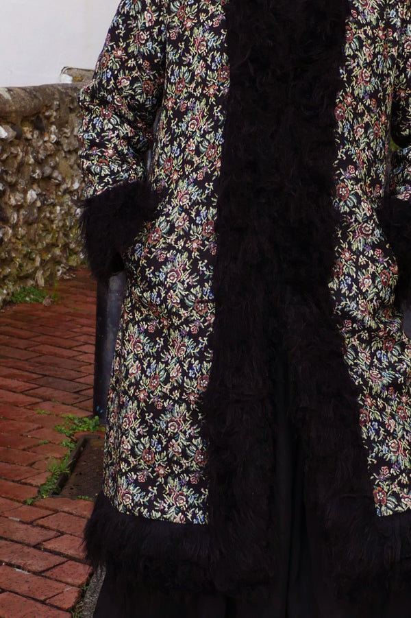 Audrey wears our Fleetwood Coat in Tapestry Black Floral. A 1970s Penny Lane inspired design with fur trim and vintage floral detailing. By All About Audrey