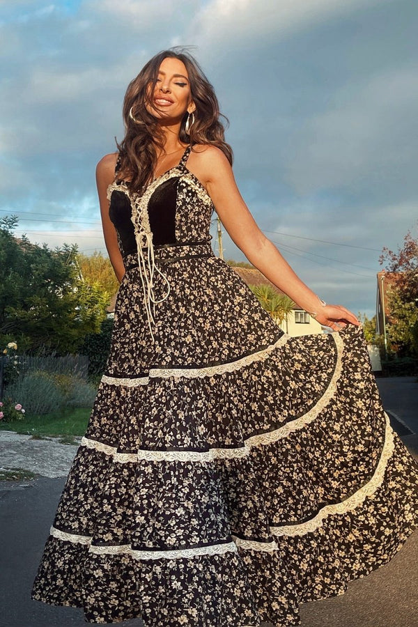 Model wears our Darcy Maxi Dress in Gothic Galloway Black, showing off the full lace tiered maxi skirt and fitted velvet bodice. All in a contrasting wildflower daisy print by All About Audrey