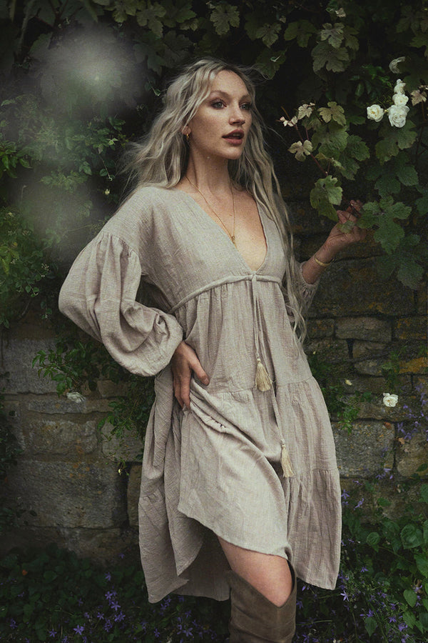 Model wears our Gypsophila Midi Dress in Stone, a beautiful smock style dress with a plunging V - neckline, drawstring waist and elegant balloon sleeves. An ethereal bohemian style perfect for dressing up or down by All About Audrey